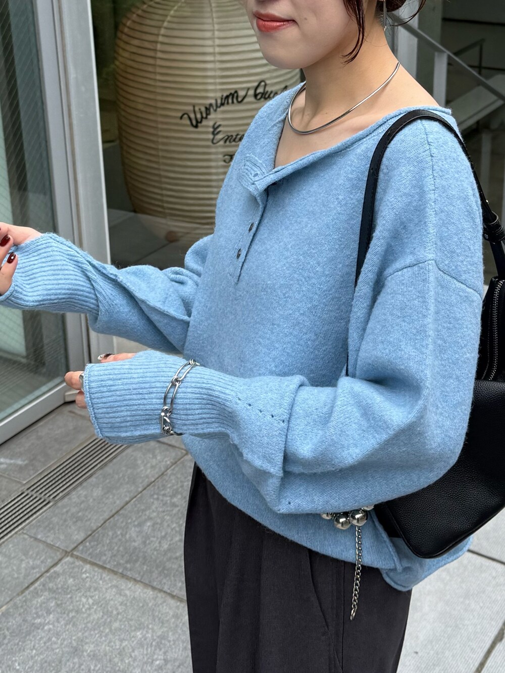 ブルー系のニット/セーター、グレー系のスラックスを着用したレディースの秋コーディネートの4枚目の写真