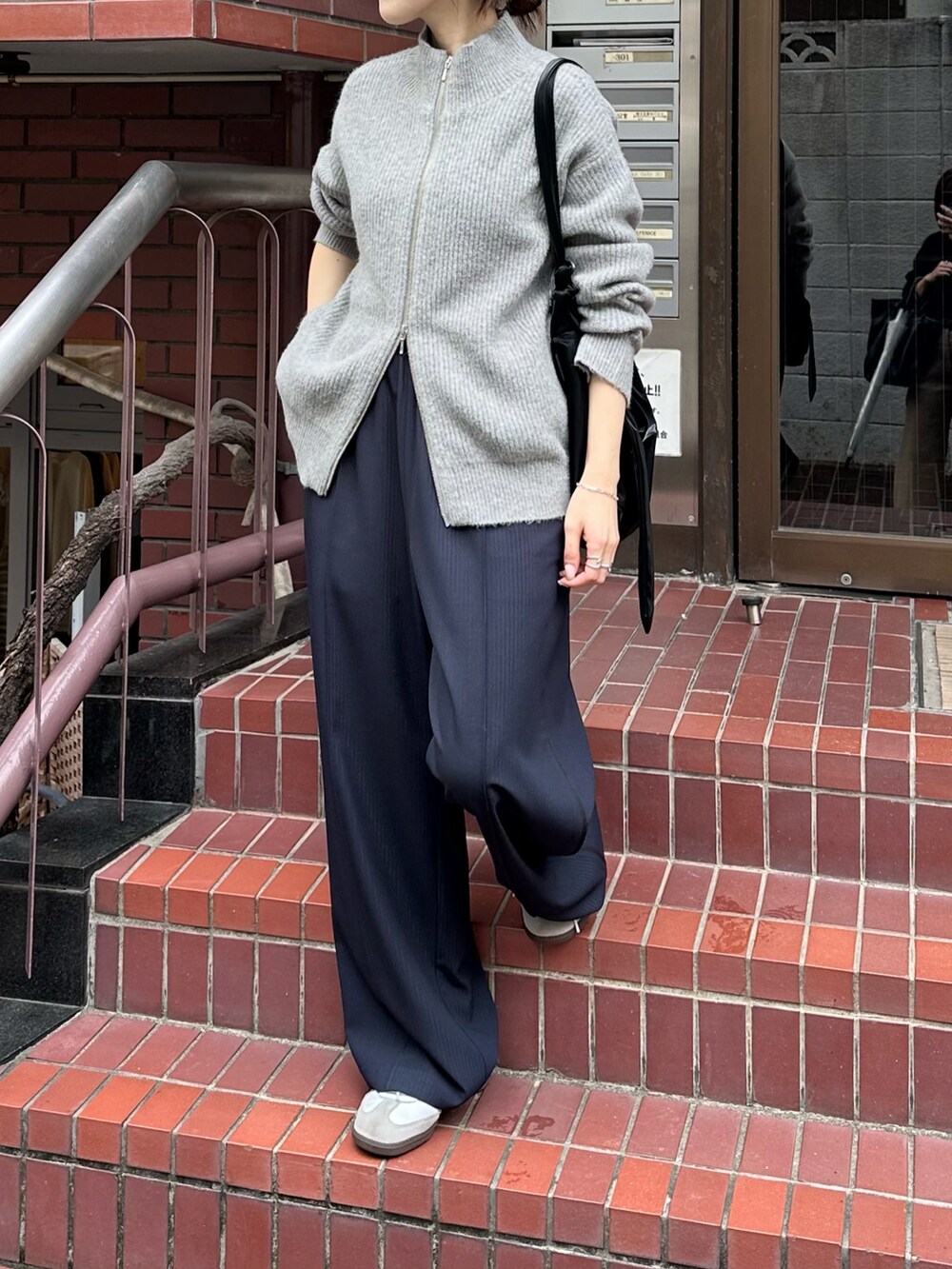 グレー系のカーディガン/ボレロ、ブルー系のスラックス、ブラック系のショルダーバッグを着用したレディースの秋コーディネートの3枚目の写真