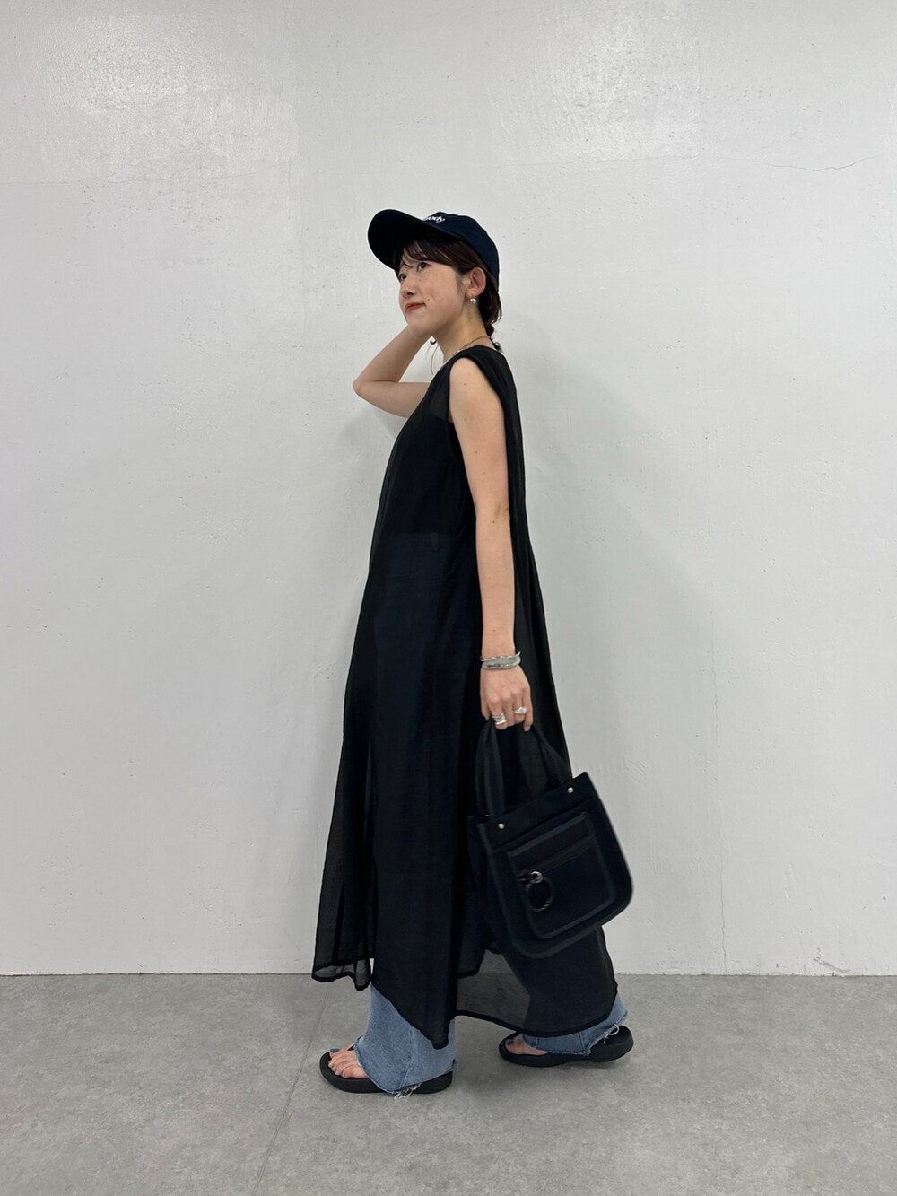 ブラック系のワンピース、ブラック系のトートバッグ、ブルー系のデニムパンツを着用したレディースの夏コーディネートの3枚目の写真