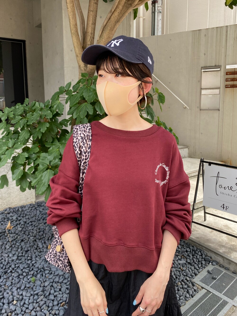 ブラック系のスカート、ブラウン系のショルダーバッグ、レッド系のスウェットを着用したレディースの夏コーディネートの3枚目の写真