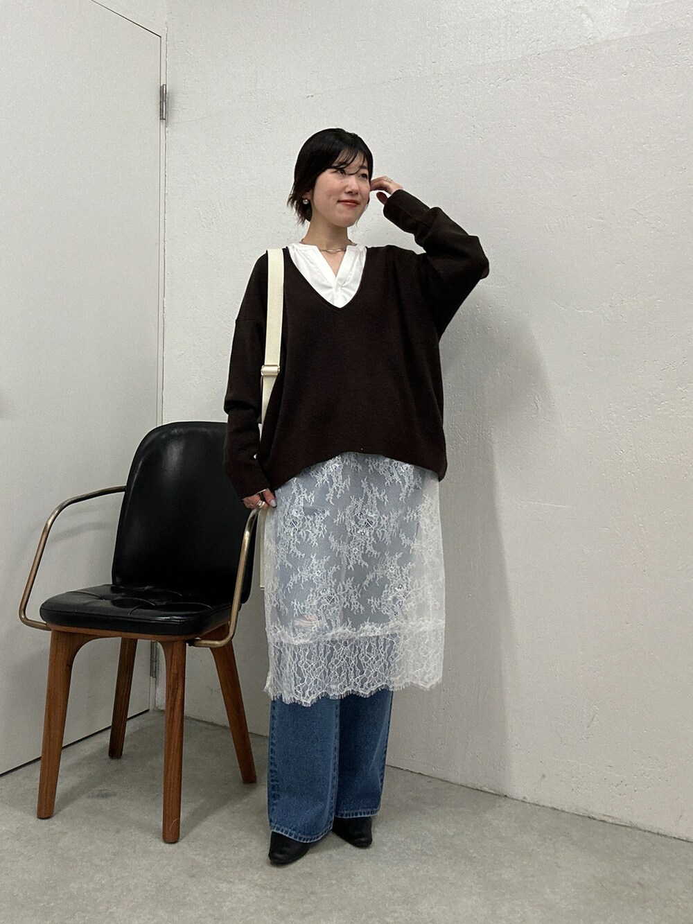 ブラウン系のニット/セーター、ホワイト系のチュニック、ブルー系のデニムパンツを着用したレディースの冬コーディネートの4枚目の写真