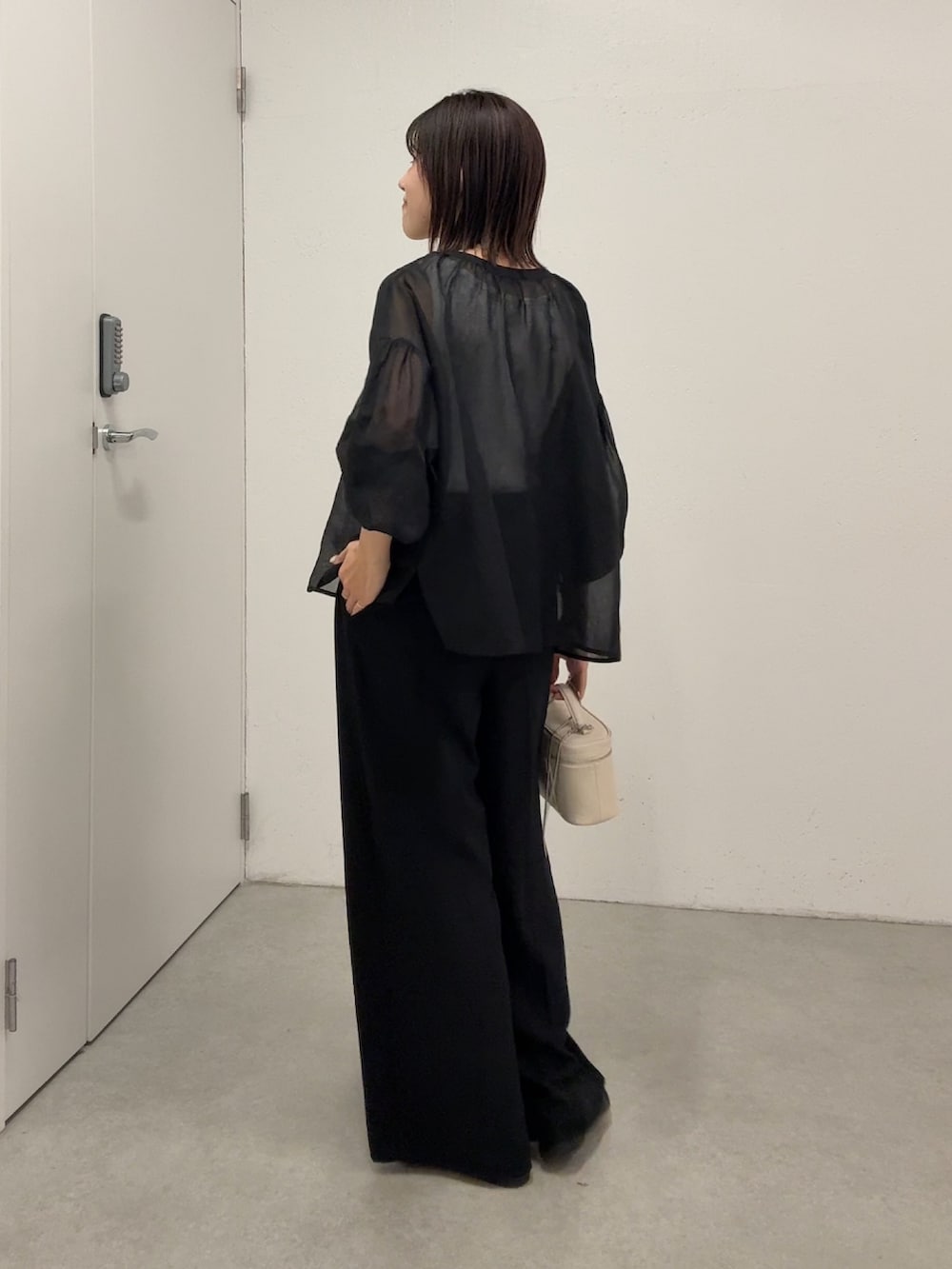 ブラック系のシャツ/ブラウス、ブラック系のスラックス、ホワイト系のショルダーバッグを着用したレディースの春コーディネートの4枚目の写真