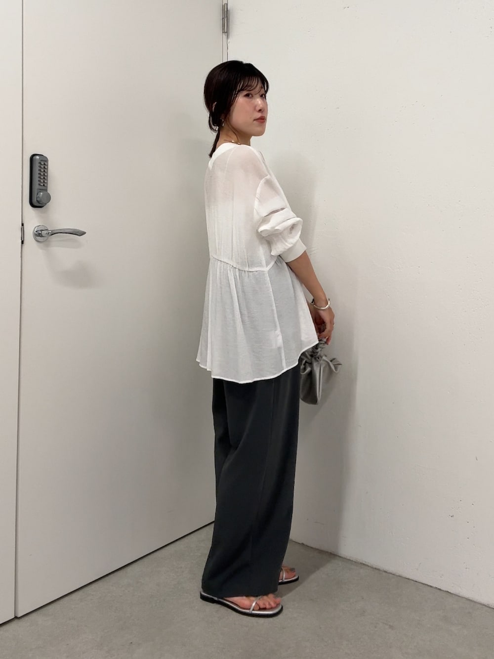 ホワイト系のシャツ/ブラウス、グレー系のスラックス、シルバー系のショルダーバッグを着用したレディースの春コーディネートの2枚目の写真