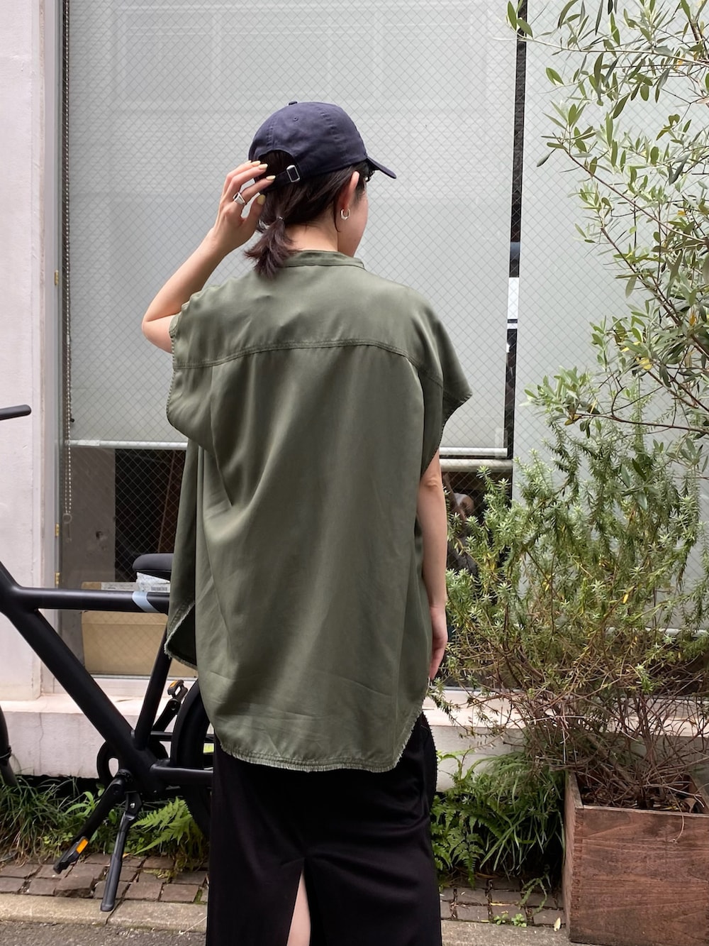 ブラック系のスカート、グリーン系のシャツ/ブラウスを着用したレディースの夏コーディネートの2枚目の写真