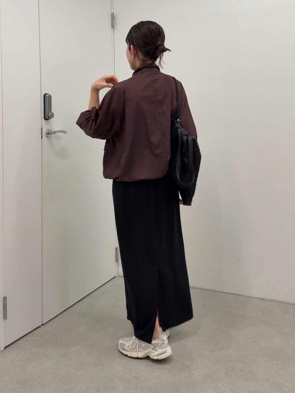 ブラウン系のマウンテンパーカー、ブラック系のスカート、ブラック系のトートバッグを着用したレディースの春コーディネートの4枚目の写真