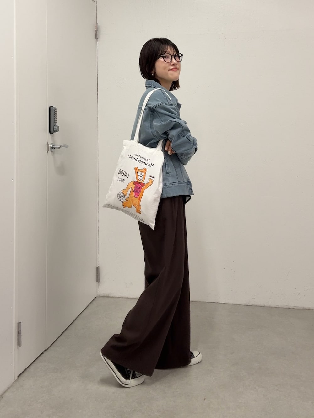 ブラウン系のスラックス、ブルー系のデニムジャケット、ブラック系のシャツ/ブラウスを着用したレディースの春コーディネートの3枚目の写真