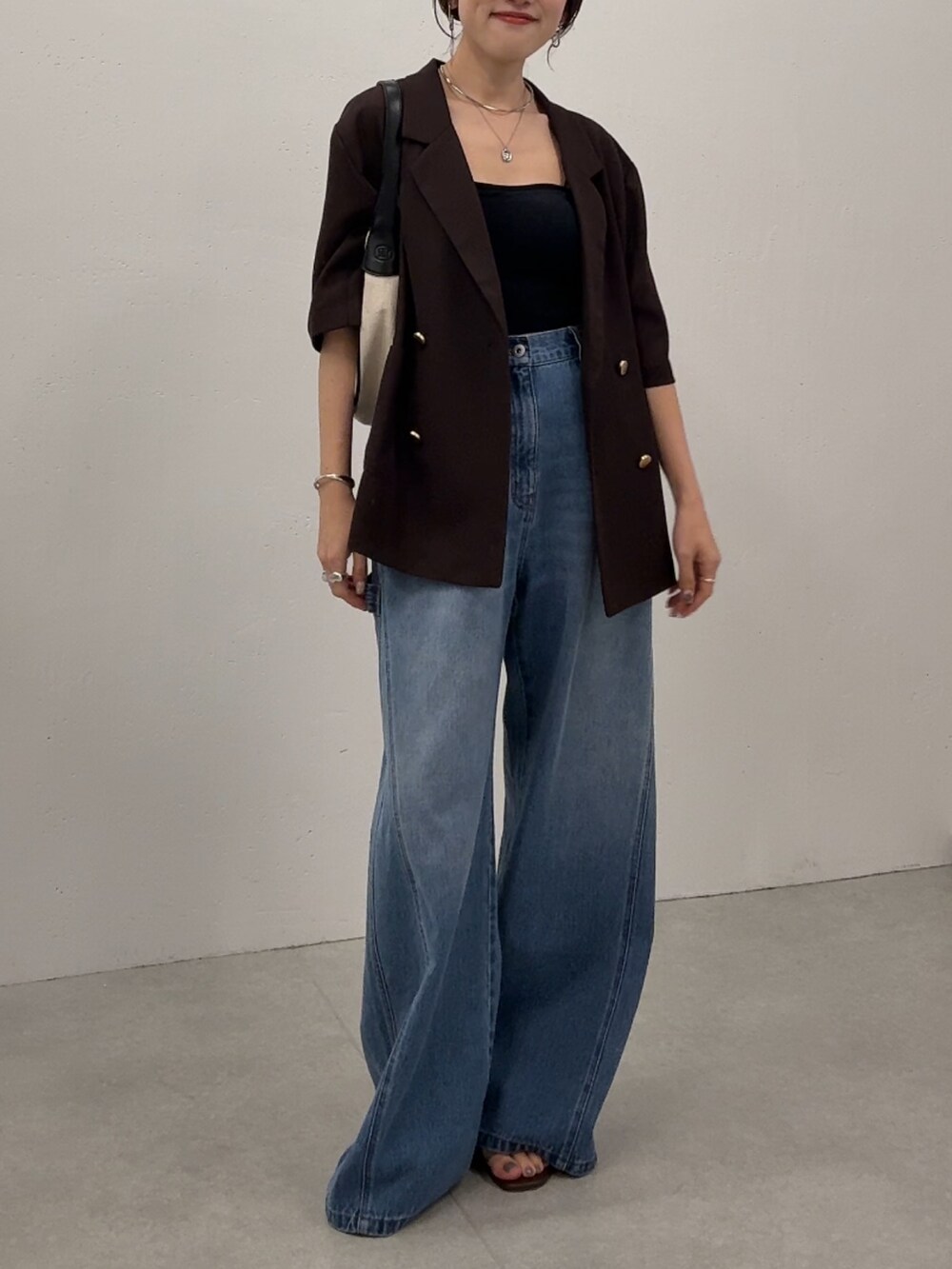 ブラウン系のテーラードジャケット、ブルー系のデニムパンツ、ゴールド系のネックレスを着用したレディースの夏コーディネートの4枚目の写真