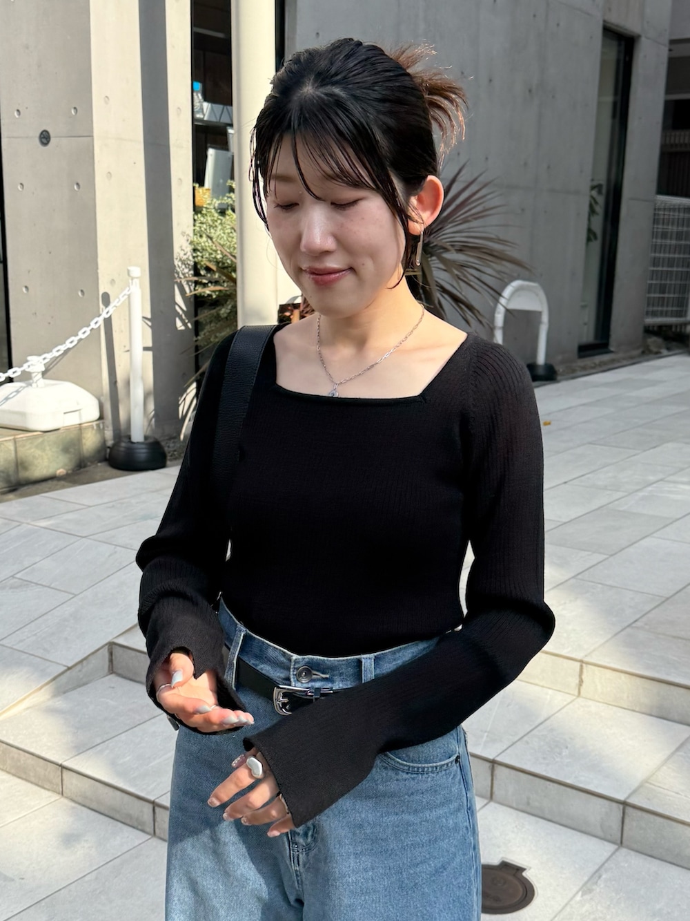 ブルー系のデニムパンツ、ブラック系のニット/セーター、ブラック系のパンプスを着用したレディースの秋コーディネートの7枚目の写真