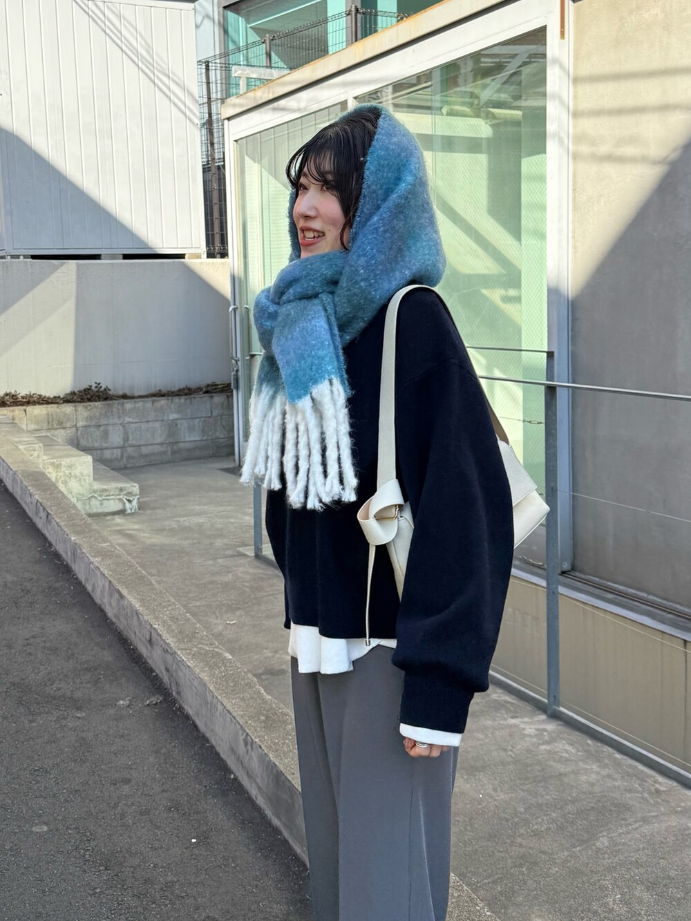 ブルー系のニット/セーター、グレー系のその他パンツ、ホワイト系のTシャツ/カットソーを着用したレディースの冬コーディネートの4枚目の写真