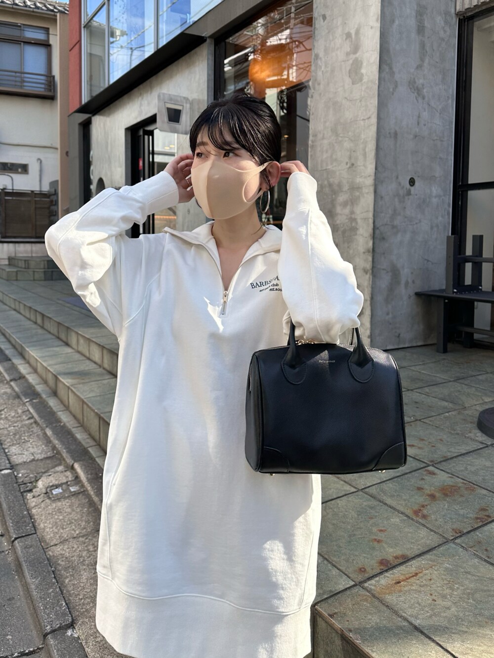 ホワイト系のスウェット、ブラック系のボストンバッグ、ブラック系のブーツを着用したレディースの秋コーディネートの3枚目の写真