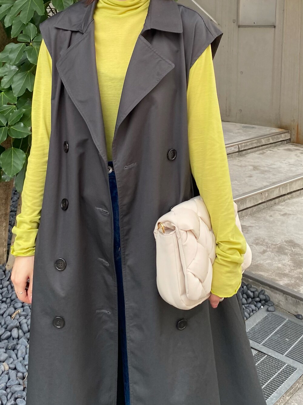 グレー系のトレンチコート、グリーン系のTシャツ/カットソー、ホワイト系のショルダーバッグを着用したレディースの夏コーディネートの4枚目の写真