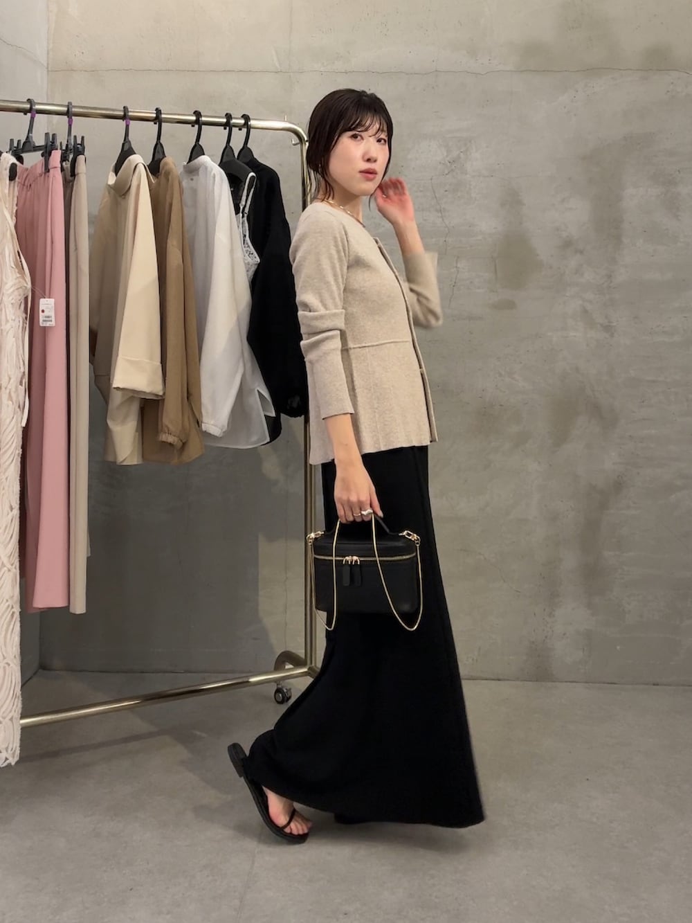 ベージュ系のカーディガン/ボレロ、ブラック系のスカート、ブラック系のショルダーバッグを着用したレディースの春コーディネートの2枚目の写真