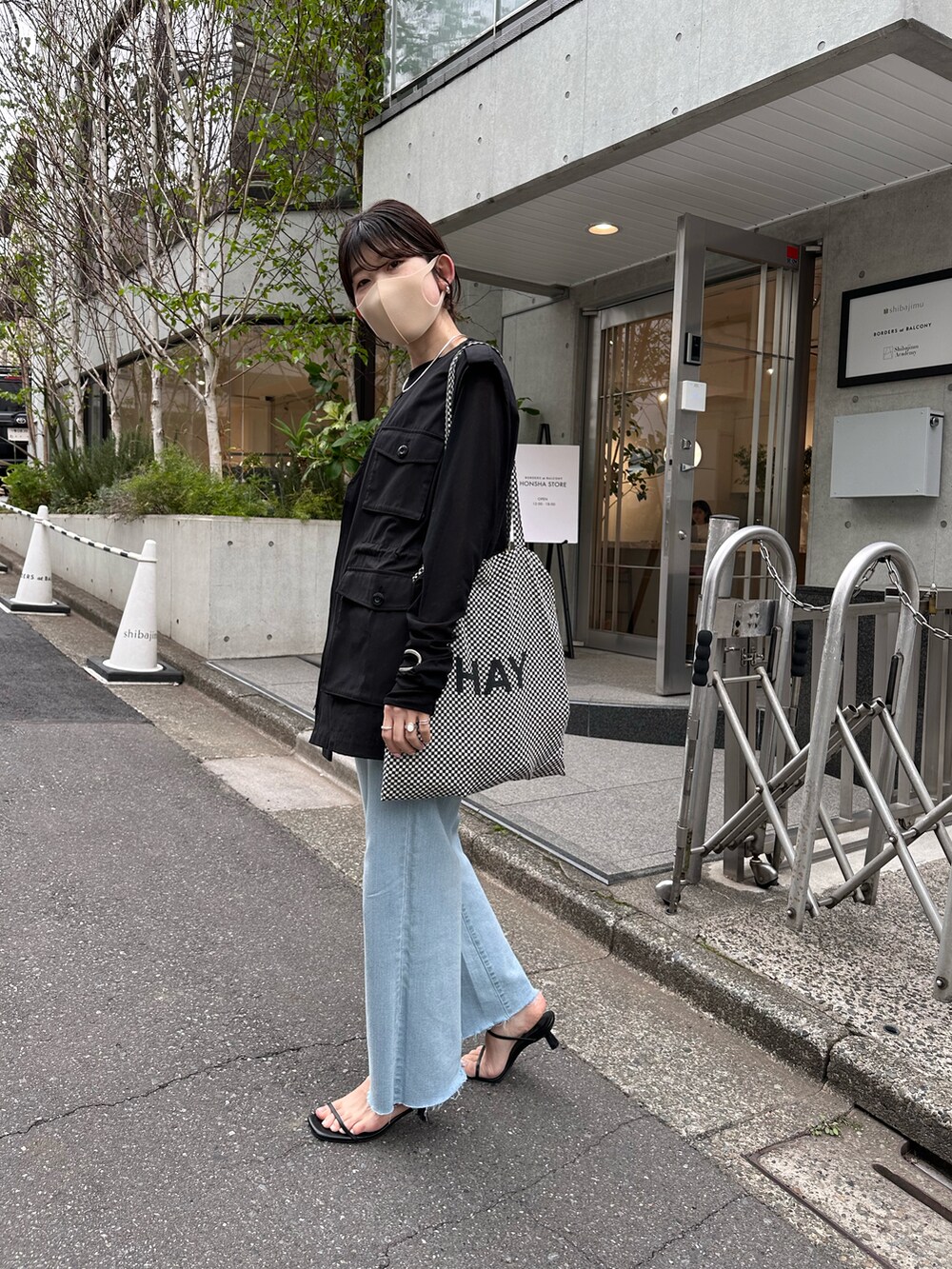 ブラック系のTシャツ/カットソー、ブラック系のベスト、ブルー系のデニムパンツを着用したレディースの春コーディネートの3枚目の写真