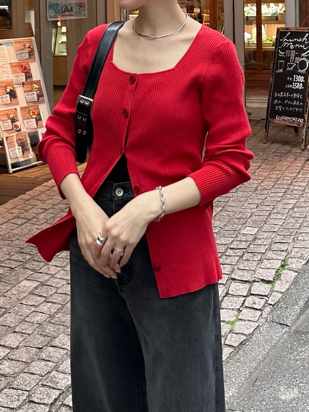 レッド系のニット/セーター、ブラック系のデニムパンツ、ブラック系のバッグを着用したレディースの夏コーディネートの2枚目の写真