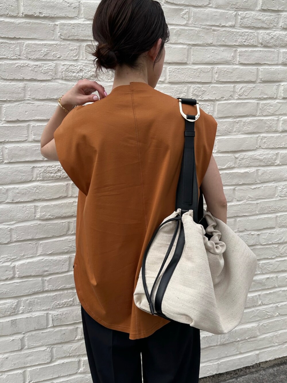 イエロー系のTシャツ/カットソー、ブラック系のスラックス、ブラック系のサンダルを着用したレディースの春コーディネートの3枚目の写真