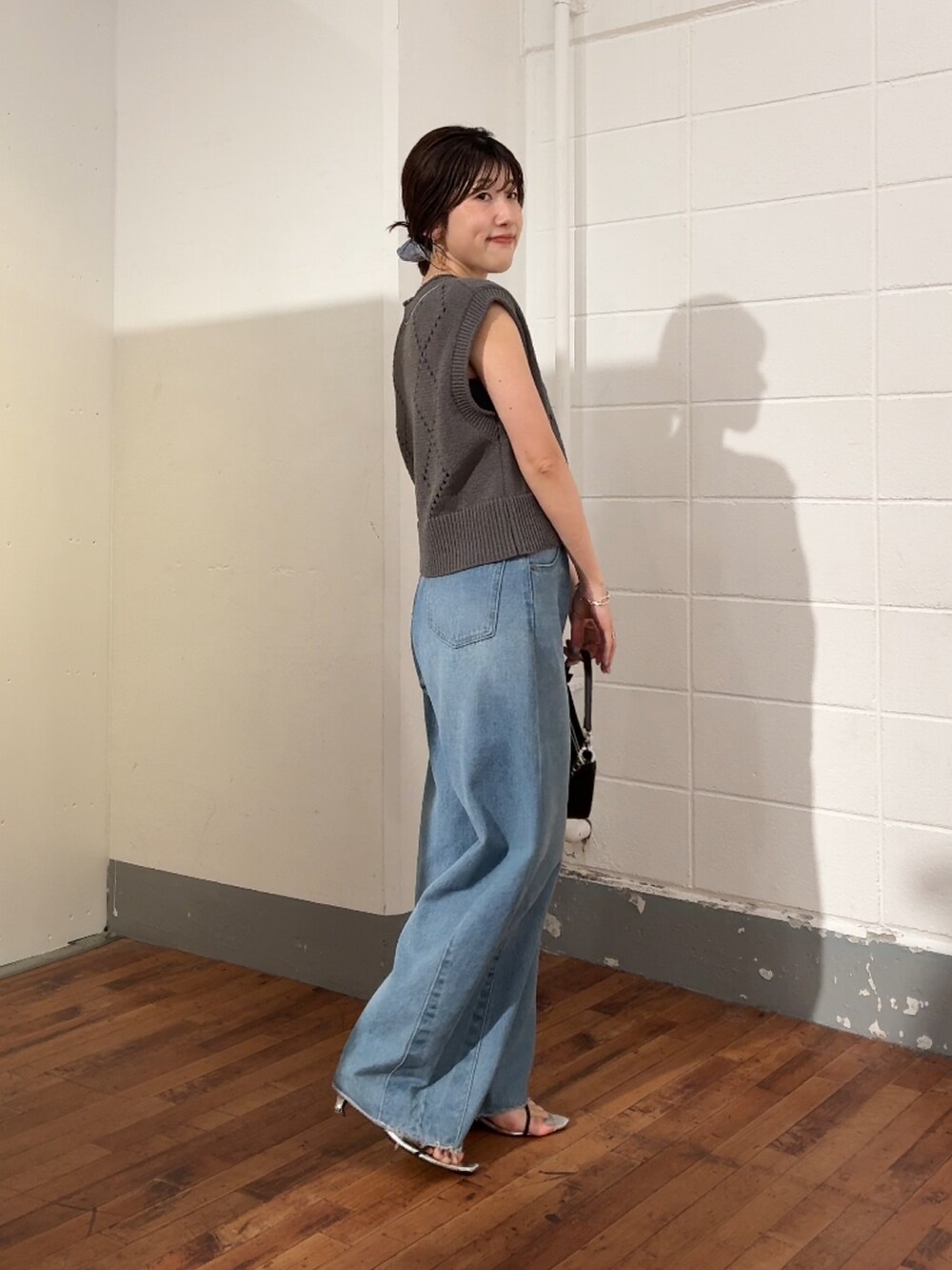 グレー系のニット/セーター、ブルー系のデニムパンツ、ブラック系のショルダーバッグを着用したレディースの夏コーディネートの2枚目の写真