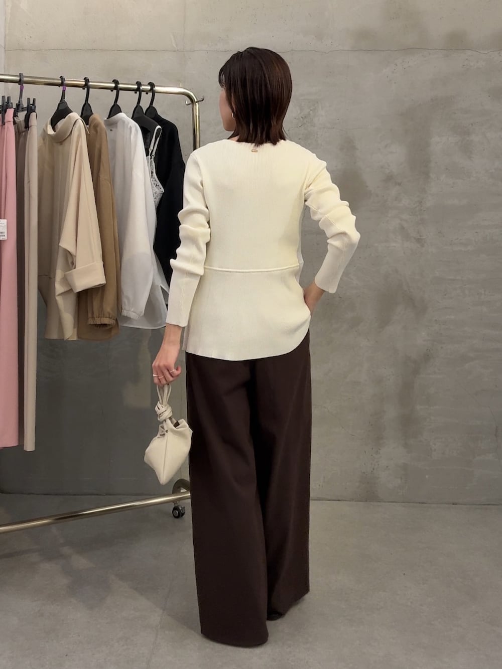 ホワイト系のカーディガン/ボレロ、ブラウン系のスラックス、ホワイト系のショルダーバッグを着用したレディースの春コーディネートの2枚目の写真