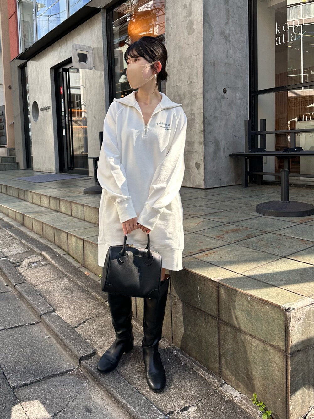 ホワイト系のスウェット、ブラック系のボストンバッグ、ブラック系のブーツを着用したレディースの秋コーディネートの4枚目の写真