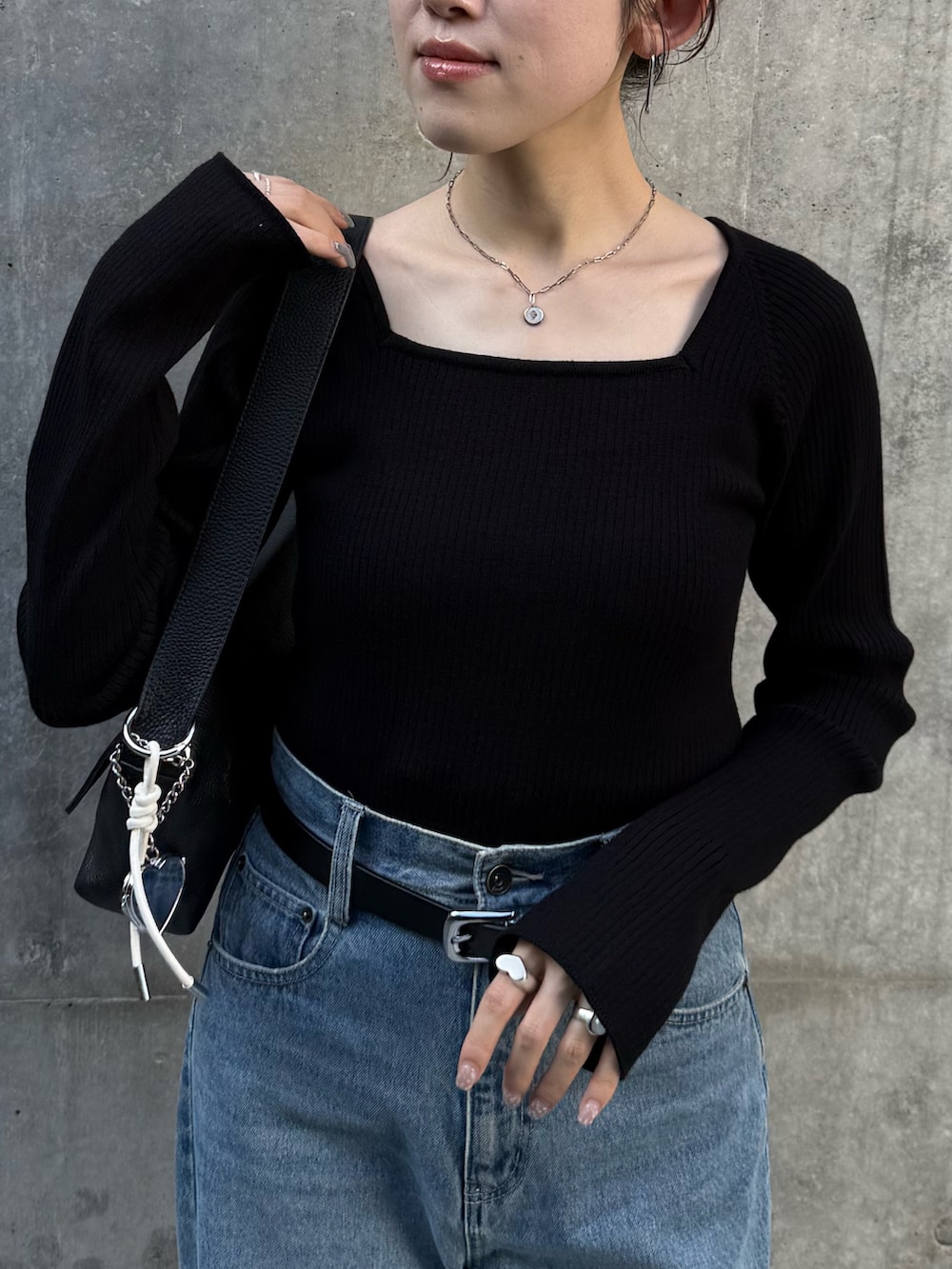 ブルー系のデニムパンツ、ブラック系のニット/セーター、ブラック系のパンプスを着用したレディースの秋コーディネートの5枚目の写真