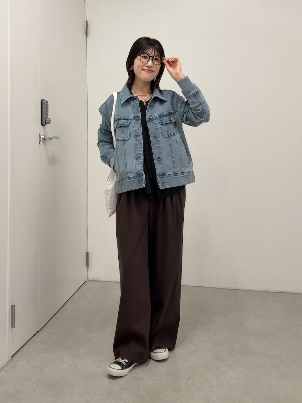 ブラウン系のスラックス、ブルー系のデニムジャケット、ブラック系のシャツ/ブラウスを着用したレディースの春コーディネートの5枚目の写真