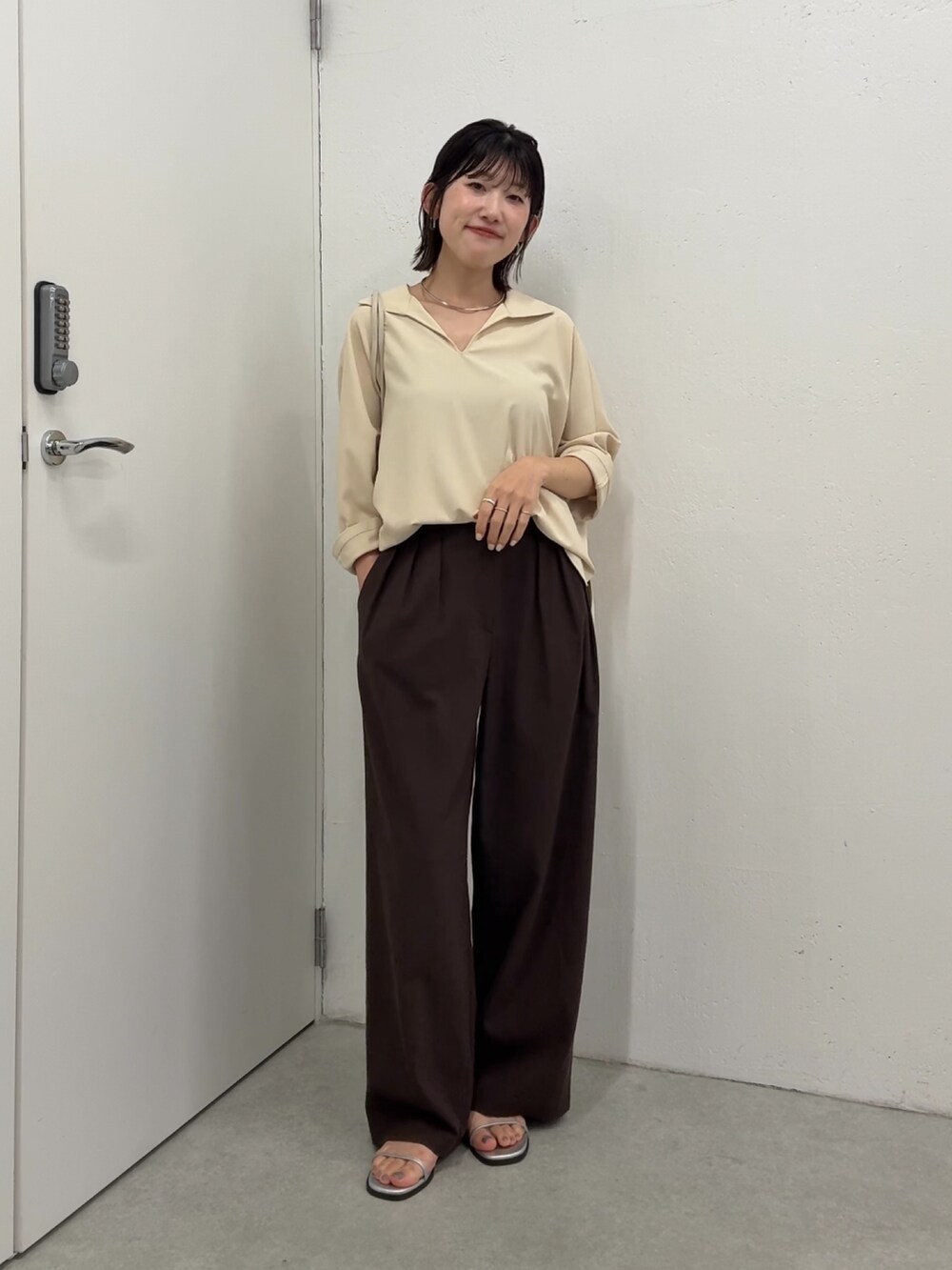 イエロー系のシャツ/ブラウス、ブラウン系のスラックス、ホワイト系のショルダーバッグを着用したレディースの春コーディネートの4枚目の写真