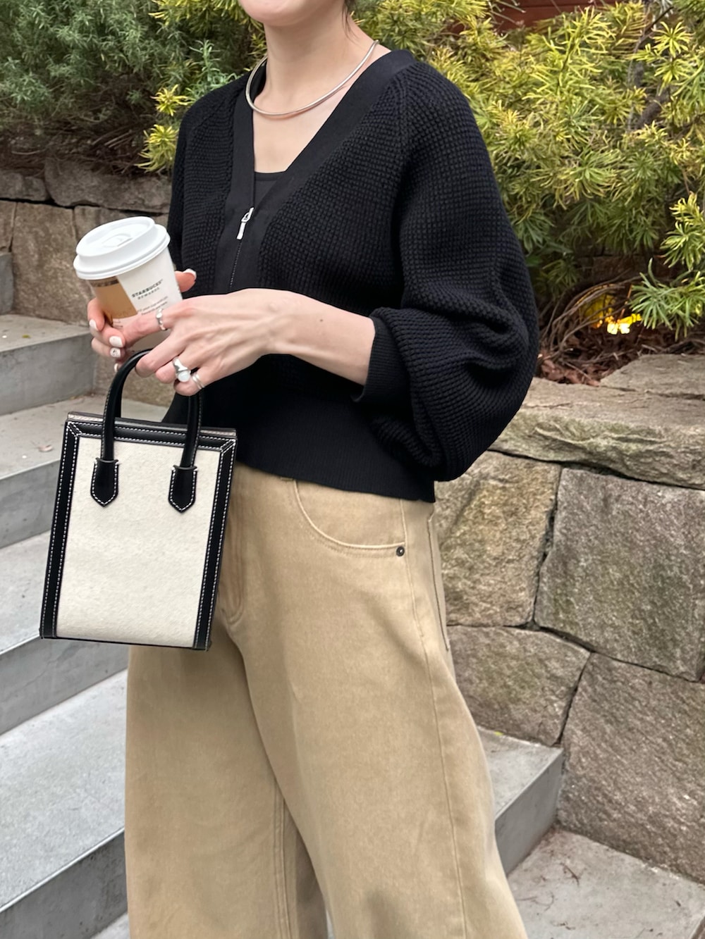 ブラック系のショルダーバッグ、ブラック系のカーディガン/ボレロ、ベージュ系のデニムパンツを着用したレディースの春コーディネートの2枚目の写真