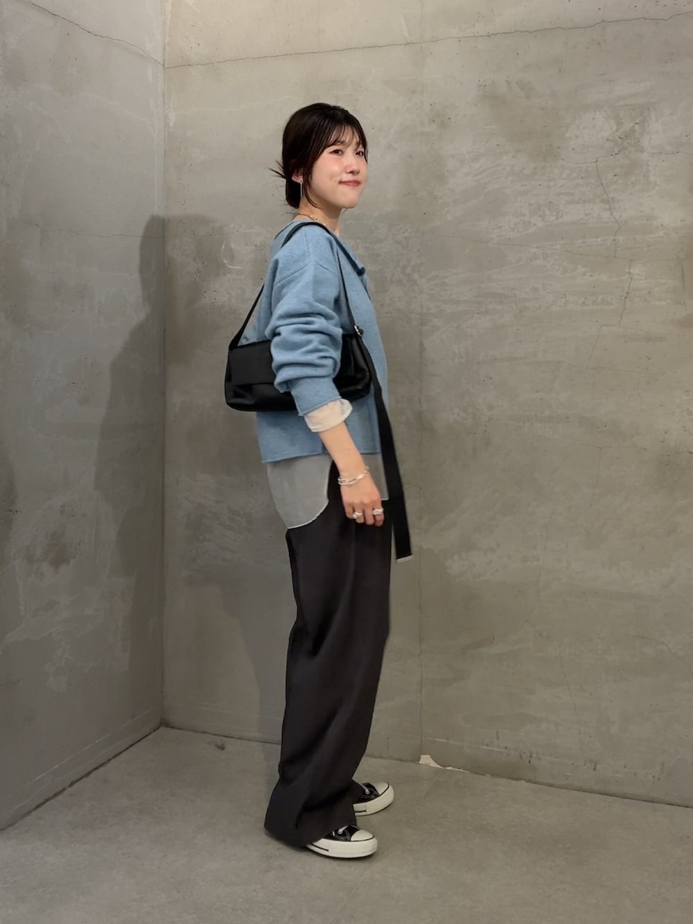 ブルー系のニット/セーター、ホワイト系のTシャツ/カットソー、グレー系のスラックスを着用したレディースの秋コーディネートの3枚目の写真