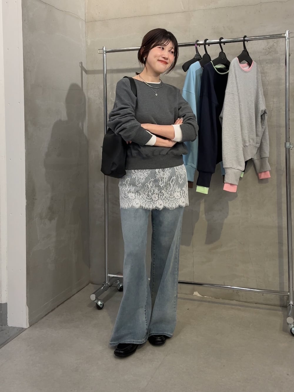 グレー系のスウェット、ホワイト系のスカート、ブルー系のデニムパンツを着用したレディースの春コーディネートの3枚目の写真