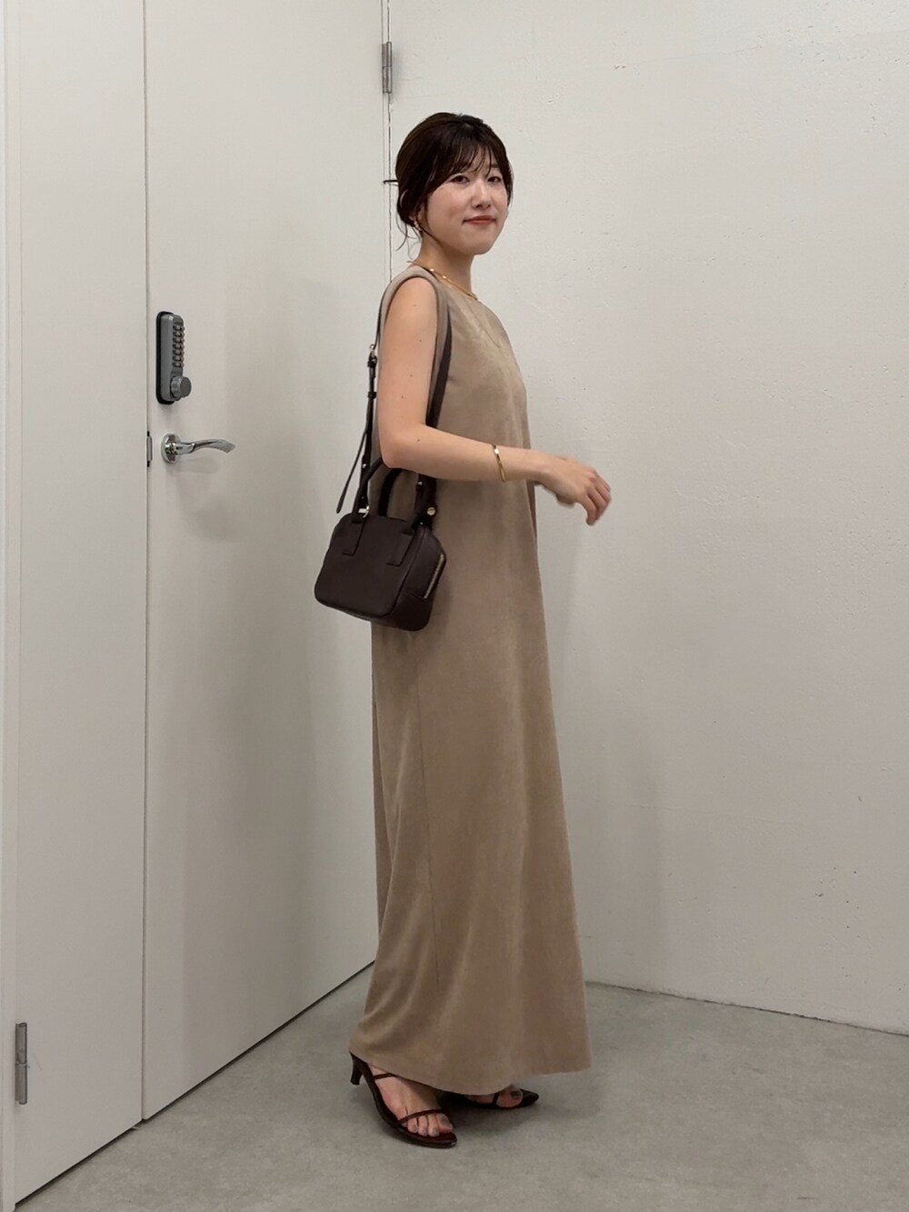 ベージュ系のワンピース、ブラウン系のショルダーバッグ、ゴールド系のネックレスを着用したレディースの夏コーディネートの3枚目の写真