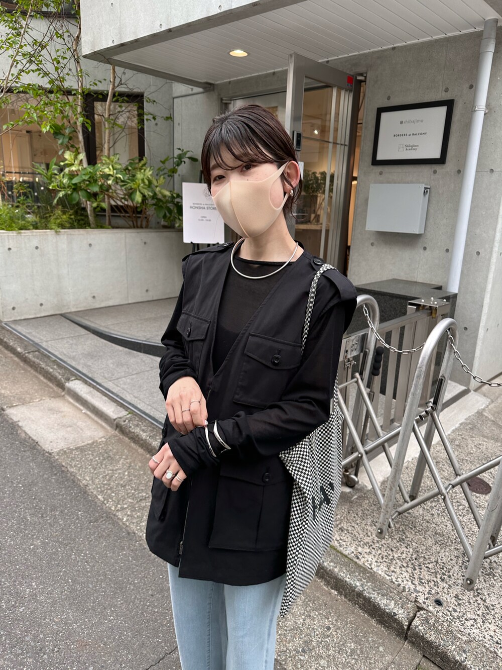 ブラック系のTシャツ/カットソー、ブラック系のベスト、ブルー系のデニムパンツを着用したレディースの春コーディネートの2枚目の写真