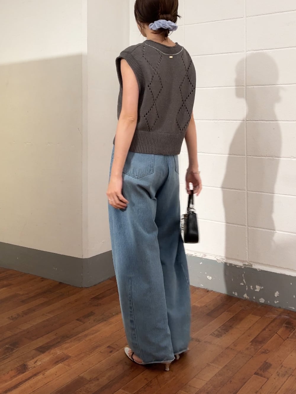 グレー系のニット/セーター、ブルー系のデニムパンツ、ブラック系のショルダーバッグを着用したレディースの夏コーディネートの3枚目の写真