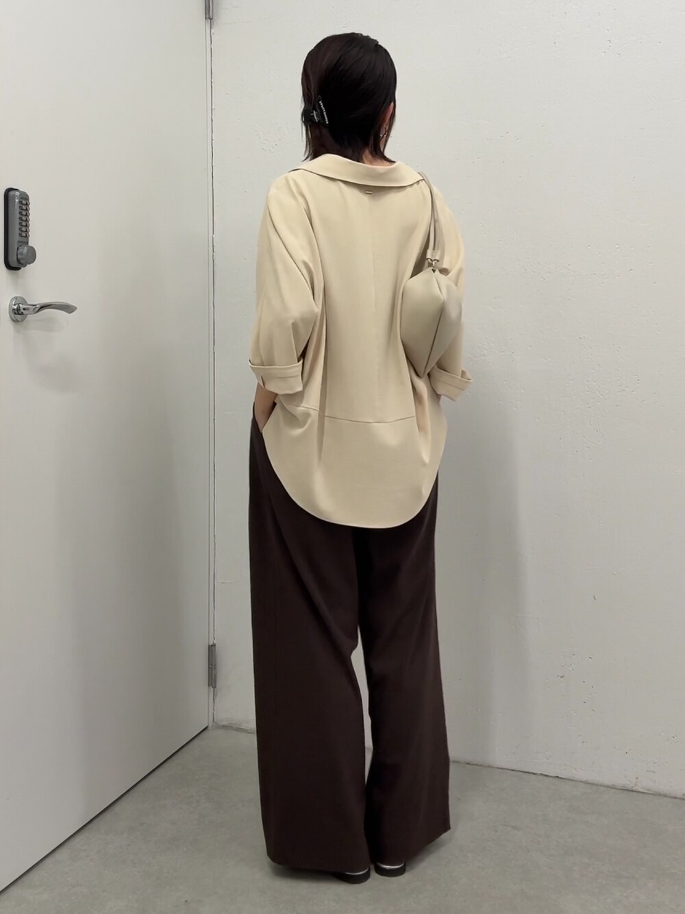 イエロー系のシャツ/ブラウス、ブラウン系のスラックス、ホワイト系のショルダーバッグを着用したレディースの春コーディネートの3枚目の写真