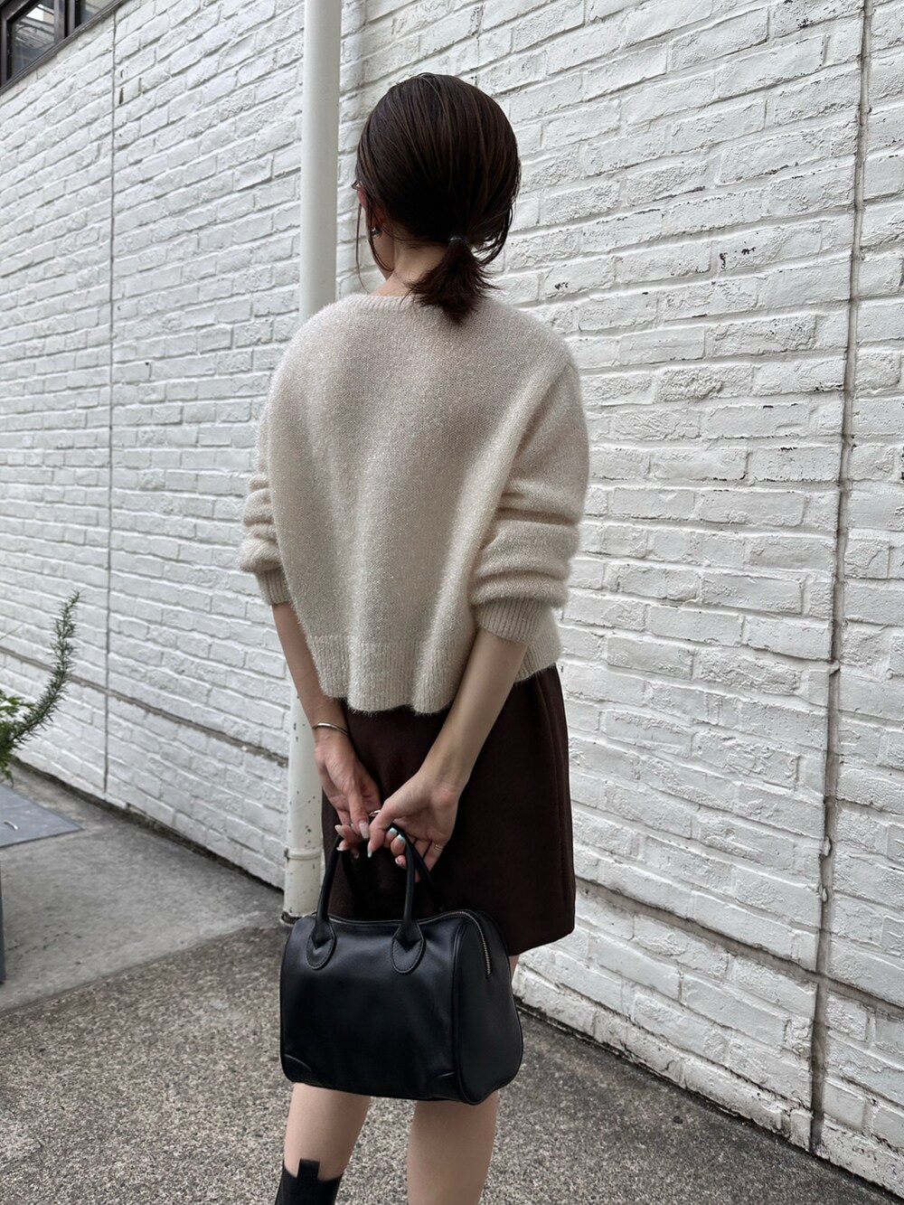 ホワイト系のカーディガン/ボレロ、グレー系のスカート、ブラック系のボストンバッグを着用したレディースの秋コーディネートの3枚目の写真