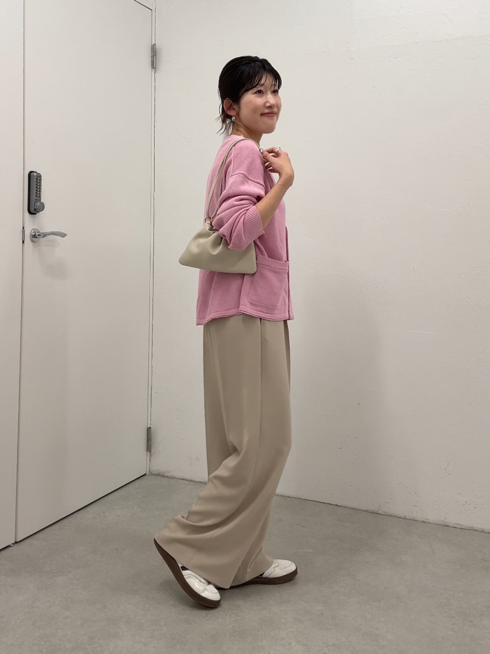 ピンク系のカーディガン/ボレロ、ベージュ系のスラックス、ホワイト系のタンクトップを着用したレディースの春コーディネートの2枚目の写真