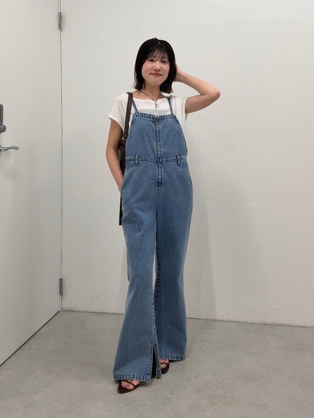 ブルー系のサロペット/オーバーオール、ホワイト系のTシャツ/カットソー、ブラウン系のショルダーバッグを着用したレディースの春コーディネートの4枚目の写真