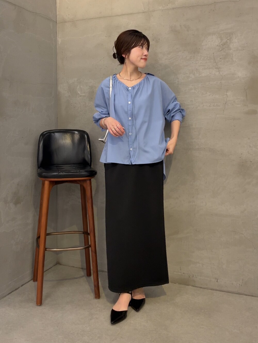 ブラック系のスカート、ブルー系のシャツ/ブラウス、シルバー系のショルダーバッグを着用したレディースの夏コーディネートの2枚目の写真