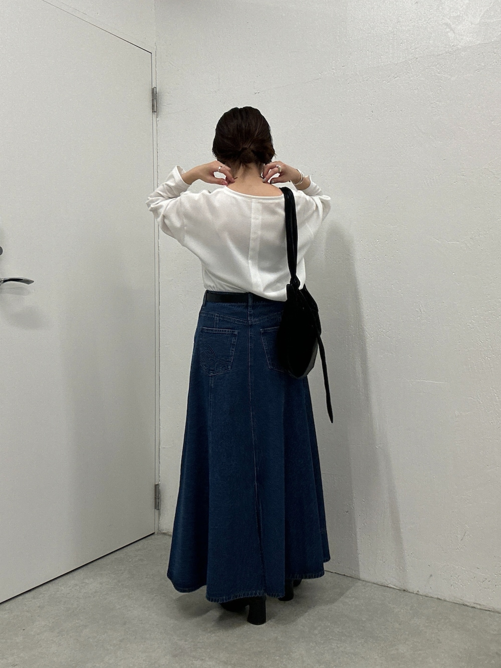 ブルー系のスカート、ホワイト系のシャツ/ブラウス、ブラック系のショルダーバッグを着用したレディースの秋コーディネートの2枚目の写真