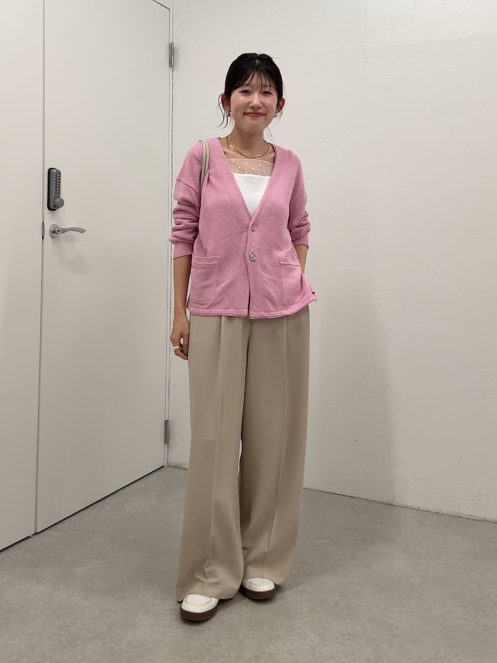 ピンク系のカーディガン/ボレロ、ベージュ系のスラックス、ホワイト系のタンクトップを着用したレディースの春コーディネートの3枚目の写真