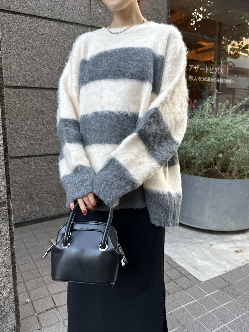 グレー系のニット/セーター、ブラック系のスカート、ブラック系のバッグを着用したレディースの秋コーディネートの4枚目の写真