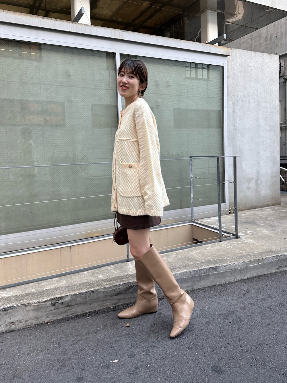 ホワイト系のカーディガン/ボレロ、ブラウン系のスカート、ベージュ系のブーツを着用したレディースの秋コーディネートの2枚目の写真