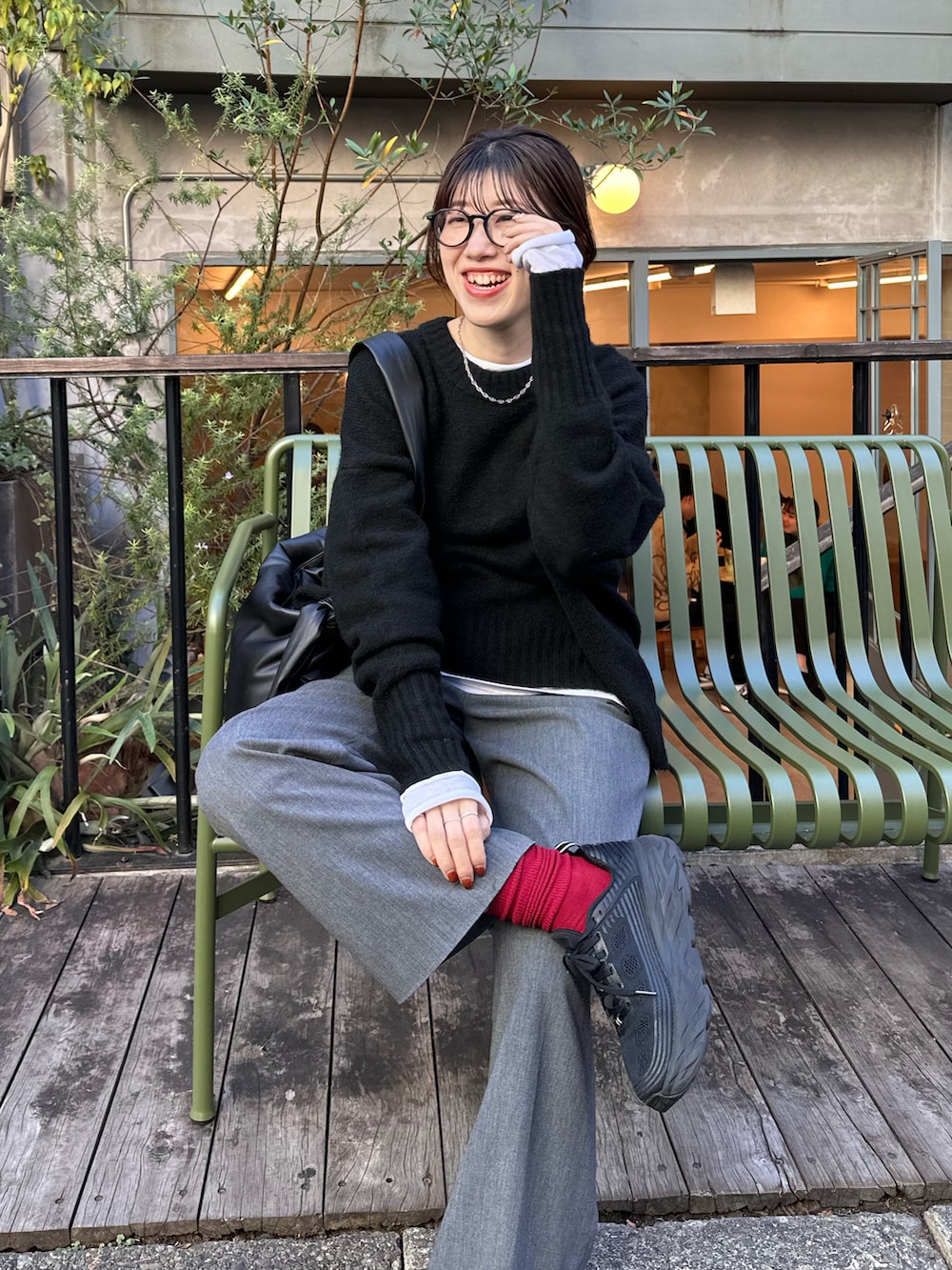 ブラック系のニット/セーター、ホワイト系のTシャツ/カットソー、ブラック系のショルダーバッグを着用したレディースの秋コーディネートの4枚目の写真