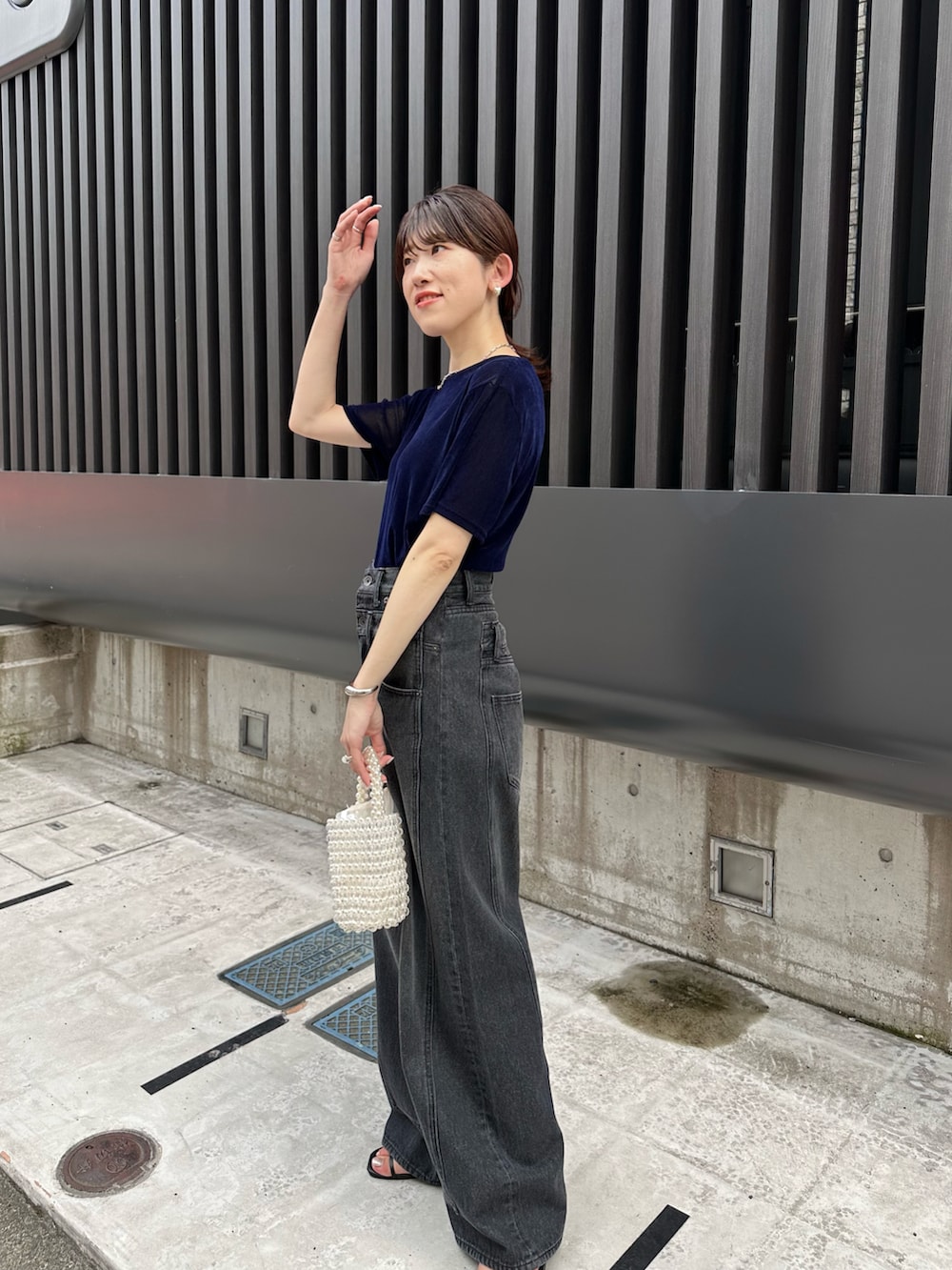 ブルー系のTシャツ/カットソー、ホワイト系のハンドバッグ、ブラック系のデニムパンツを着用したレディースの夏コーディネートの2枚目の写真