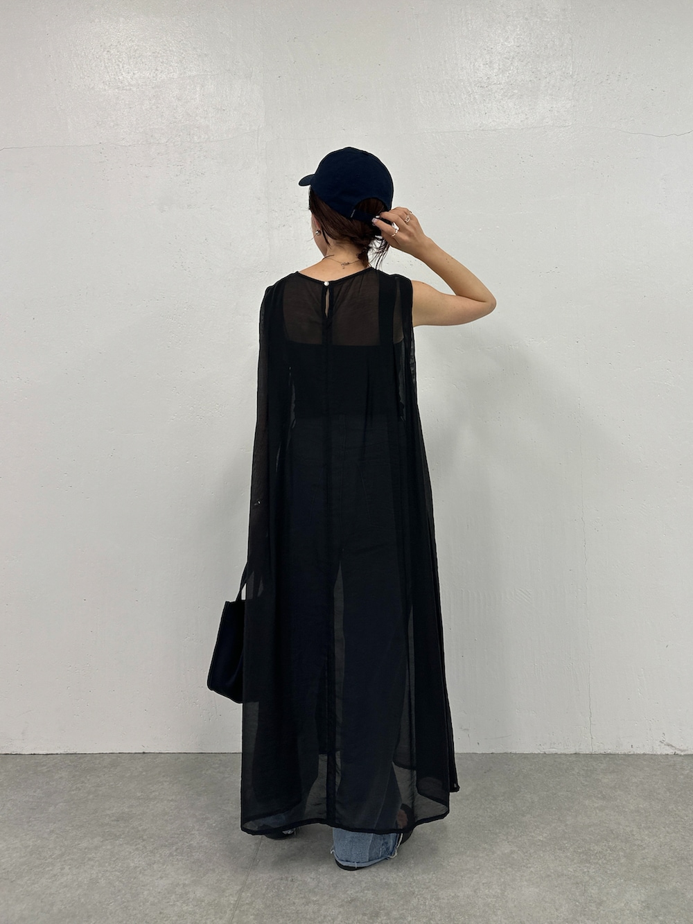 ブラック系のワンピース、ブラック系のトートバッグ、ブルー系のデニムパンツを着用したレディースの夏コーディネートの2枚目の写真