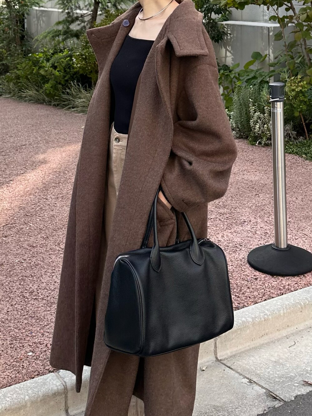 ブラック系のボストンバッグ、グレー系のその他アウター、ブルー系のデニムパンツを着用したレディースの秋コーディネートの4枚目の写真