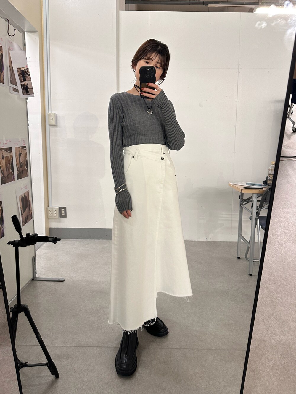 ホワイト系のデニムスカート、グレー系のニット/セーター、ブラック系のブーツを着用したレディースの秋コーディネートの2枚目の写真