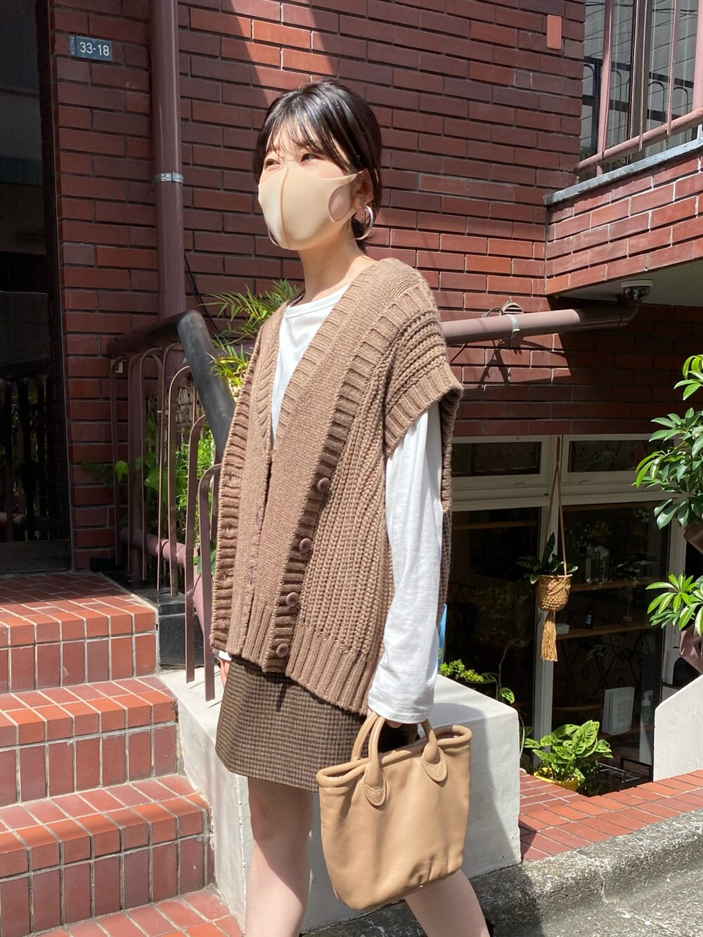 ブラウン系のベスト、ベージュ系のスカート、ブラウン系のトートバッグを着用したレディースの秋コーディネートの5枚目の写真