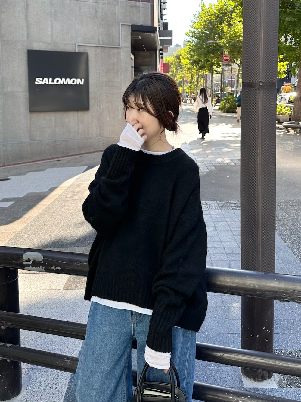 ブラック系のニット/セーター、ブラック系のバッグ、ブラック系のデニムパンツを着用したレディースの秋コーディネートの2枚目の写真