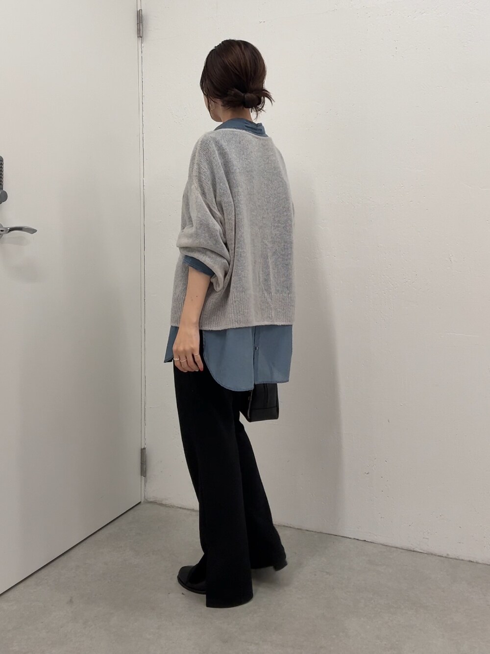 グレー系のニット/セーター、ブルー系のシャツ/ブラウス、ブラック系のボストンバッグを着用したレディースの秋コーディネートの3枚目の写真