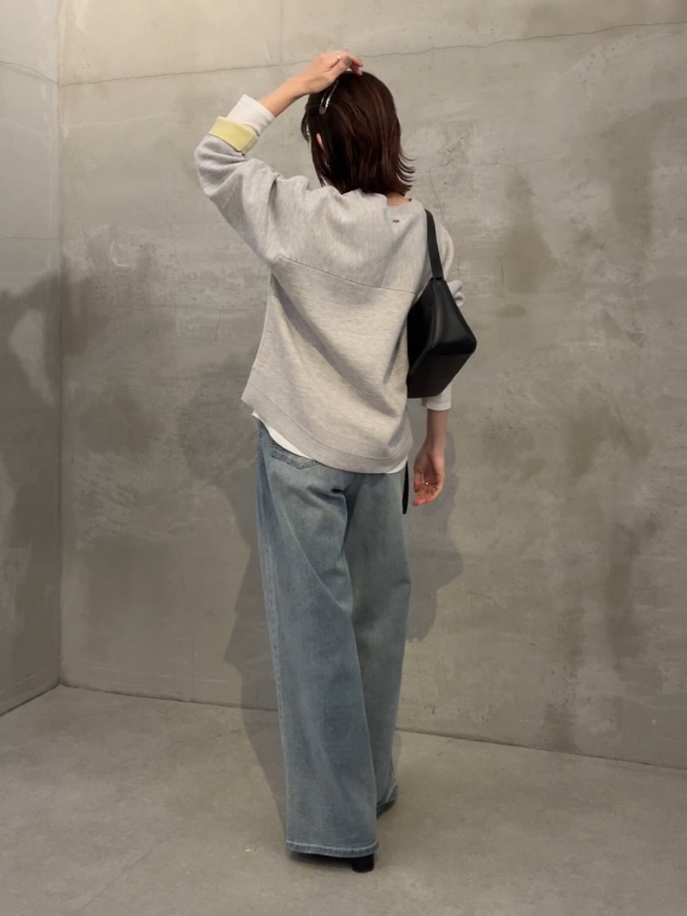 グレー系のニット/セーター、ホワイト系のTシャツ/カットソー、ブルー系のデニムパンツを着用したレディースの冬コーディネートの2枚目の写真