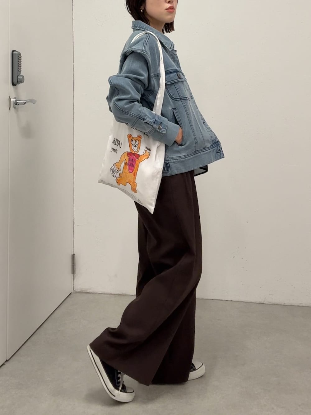 ブラウン系のスラックス、ブルー系のデニムジャケット、ブラック系のシャツ/ブラウスを着用したレディースの春コーディネートの2枚目の写真